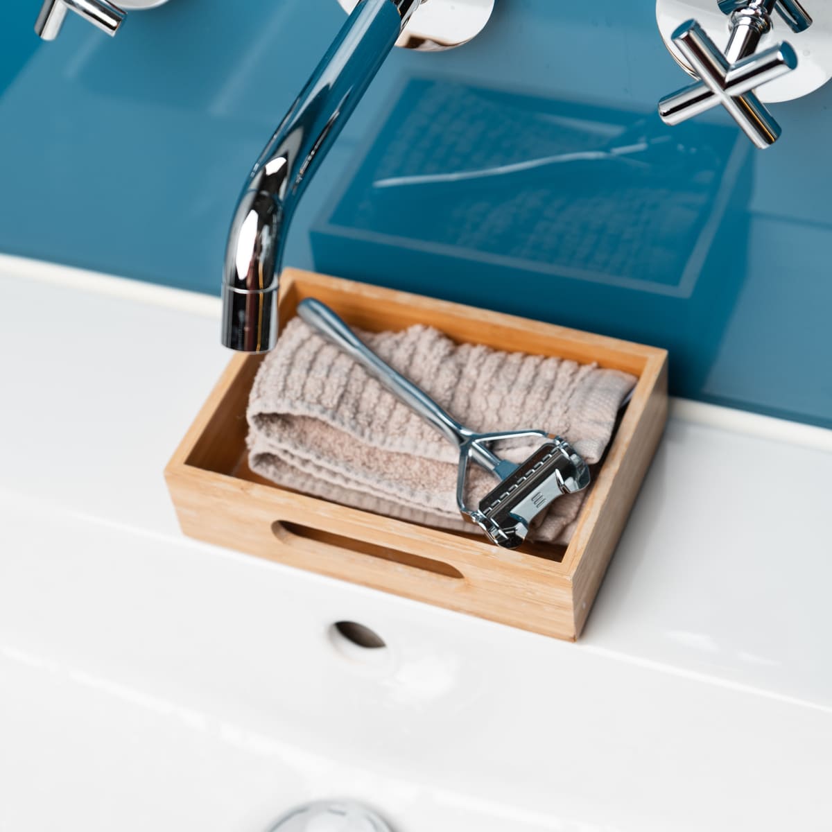 Ein Waschbecken mit Handtuch und Rasierhobel auf einer Holzbox, passend zur Nassrasur-Produktpalette von SHAVENT.