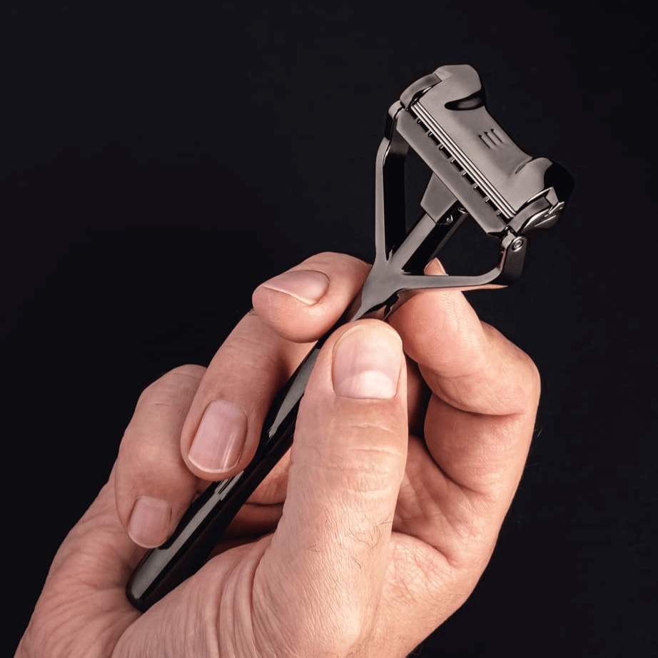 Person hält den SHAVENT Original Rasierer aus dem Reise-Set mit Ledertasche, ideal für sanfte, plastikfreie Nassrasur unterwegs.