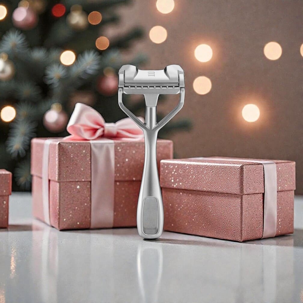 Das große SHAVENT Frauen-Geschenk-Set mit einem eleganten Metallrasierer vor rosa Geschenkboxen und festlicher Hintergrundbeleuchtung, ideal für glatte Haut und luxuriöse Pflege.